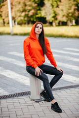 Fototapeta premium Ultra-fashion concept. Young woman of fashion wearing orange sweater and posing over orange bricks urban background. Street style. businesswoman. fashionable accessories.