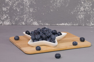Fresh blueberry in court, on a wooden table and grey background