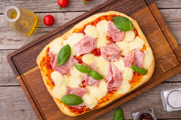 Traditional italian pizza with ham mozzarella and  basil