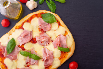 Traditional italian pizza with ham mozzarella and  basil