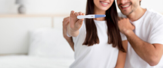 Unrecognizable happy young caucasian male and lady rejoice result and show pregnancy test - obrazy, fototapety, plakaty
