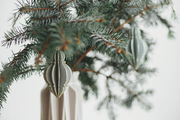 Merry Christmas! Stylish christmas ornament on fir branch in modern vase. Festive scandi decor