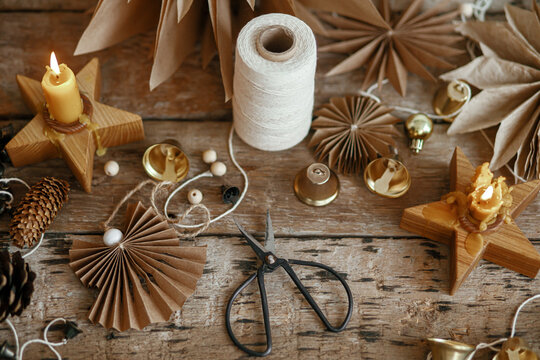 Christmas angel, stars, pine cones, candle, thread, scissors on rustic wood. Handmade scandi decor