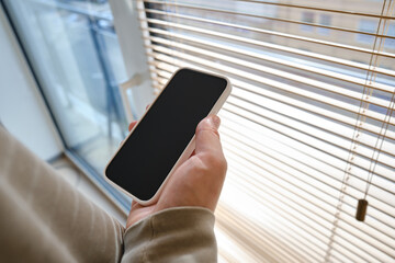A man is holding a modern smartphone, sending a text message or using an application on his mobile phone. Business concept. Smartphone close-up. Focus on the phone screen