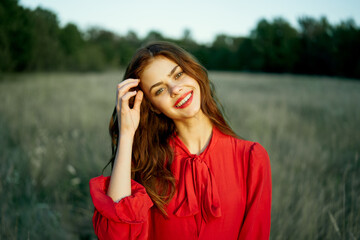 cute red-haired woman in red dress in field nature summer