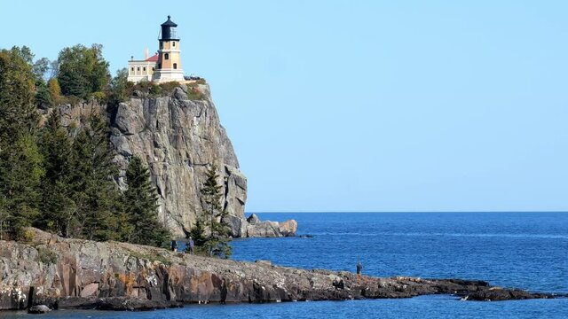 Split Rock Ligth House on the north shore of Lake Superior in Minnesota, and a few visitors on an outcrop into the blue water. A popular travel distination for tourists on the great lake.