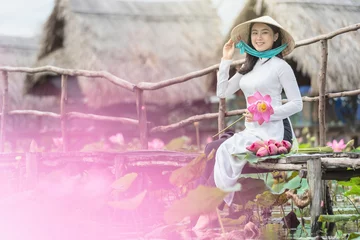 Foto op Plexiglas Portrait of beautiful vietnamese woman with traditional vietnam hat holding the pink lotus on the wooden bridge in big lotus lake, vietnam, aisan or southeast asia travel concept © THANANIT