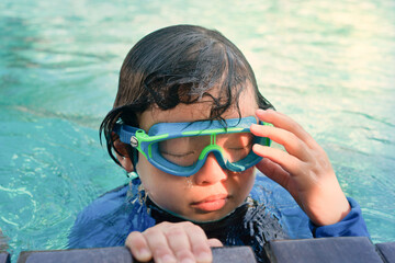 kid in goggles in swimming pool