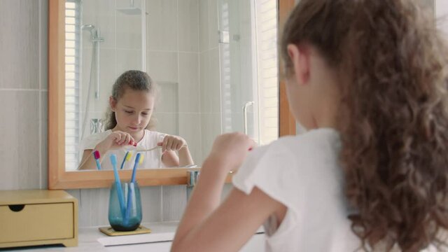 Portrait happy cute young teenage girl squeezing toothpaste onto toothbrush in her bathroom.Children daily healthcare routine. Caucasian kid with white tooth looking at mirror isolated home. Lifestyle