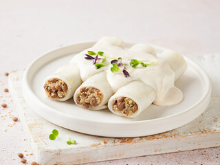 Gluten free plant based cannelloni with quinoa and lentils, vegan bechamel , light background. Macrobiotic diet. Meat alternative Vegetarian food concept.