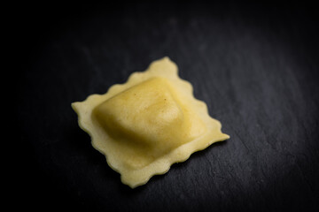 Tasty raw ravioli with flour and spinach on dark background, process of making italian ravioli