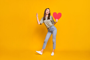 Fototapeta na wymiar Full length body size view of lovable cheerful girl holding in hands heart posing isolated over bright yellow color background