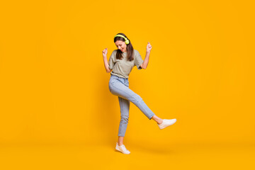 Full size photo of young pretty attractive smiling cheerful positive girl in headphones dancing isolated on yellow color background