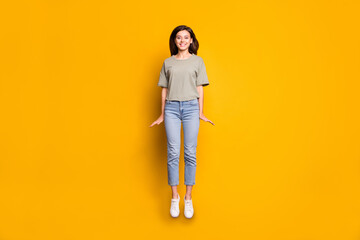 Fototapeta premium Full length body size view of pretty funny cheerful skinny girl jumping having fun isolated over bright yellow color background