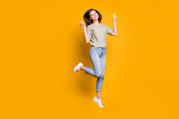 Fototapeta na wymiar Full length body size view of pretty funny cheerful girl jumping showing v-sign isolated over bright yellow color background