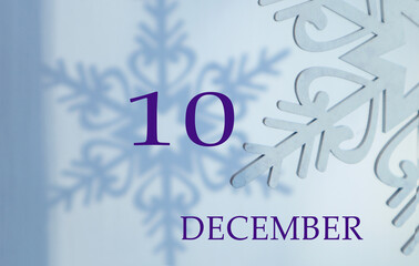 Calendar for December 10: the name of the month in English, the number 10 on a blue background of snowflakes and shadows from them.