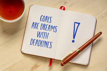 goals are dreams with deadlines - inspirational handwriting in a notebook with a cup of tea,...