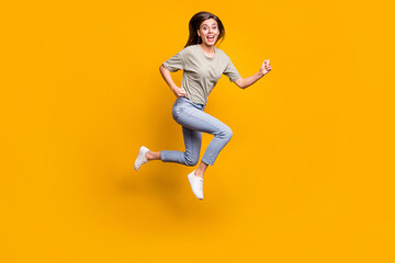 Fototapeta na wymiar Full length body size view of nice thin funny cheerful girl jumping running fast speed isolated over bright yellow color background