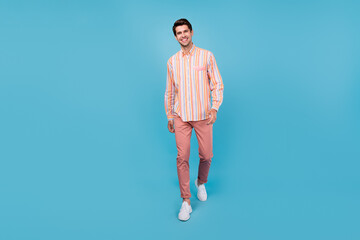 Full length photo of charming happy attractive man walk good mood smile isolated on pastel pink...