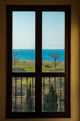 view of the sea coast through the window, a green meadow and a blue sky