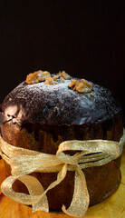 Panettone on a wooden table with a black background surrounded by Christmas ornaments and a box with gift