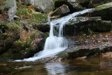Fototapeta na wymiar small waterfall hidden in the forest with autumn leaves
