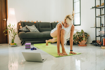 Blonde woman sitting on a floor and training by online course