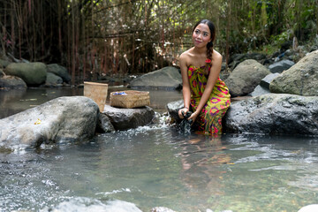 Portrait Asian young woman washing clothes at the stream.