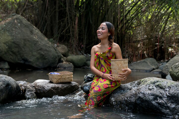 Young beautiful woman wash clothes near river in the tropical forest scene.