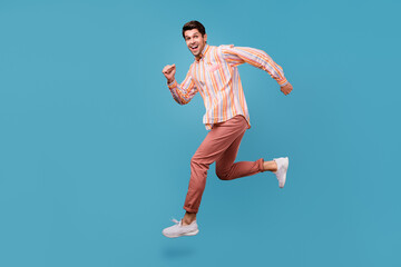 Fototapeta premium Full body profile side photo of young man happy positive smile go walk run speed jump isolated over blue color background