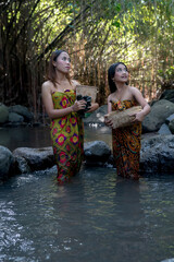 Portrait two Asian young girls washing clothes at the stream.