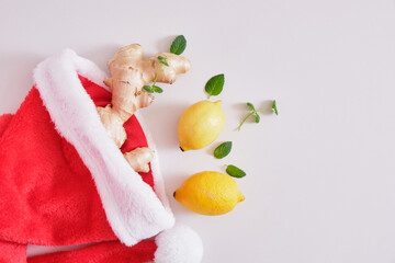 red Sants hat, ginger root, mint leaves and lemons on a gray background