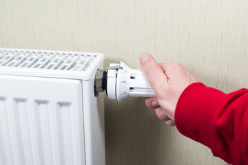 Close up, Man hand adjusting the knob of heating Radiator at home. The valve from the radiator heating. Сoncept of home heating and heat conservation.
