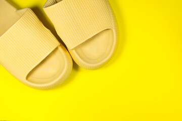 Yellow Summer Slippers on the yellow background. Pair of house indoors shoes. Minimalist, creative photo.