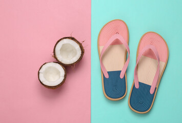 Flip flops with coconut on a blue pink background. Beach vacation concept
