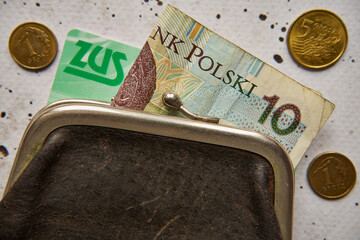 czarna portmonetka, pieniądze i legitymacja zus na betonie,polski złoty	