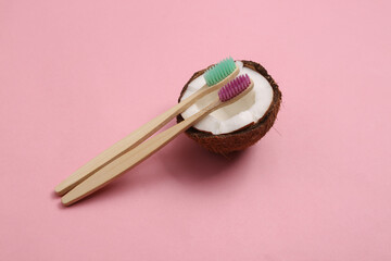 Eco toothbrushes with coconut on pink pastel background