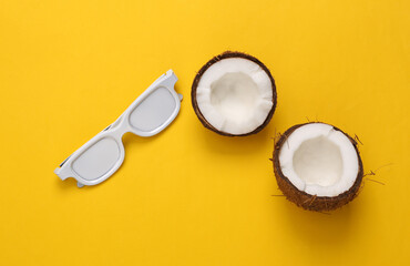 Coconut halves with white glasses on yellow background. Travel concept. Top view