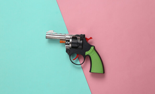 Toy gun on a blue-pink pastel background. Minimal concept. Top view