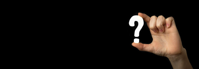Question mark sign in hand. Banner, question icon, symbol on a black background. Concept of doubt,...