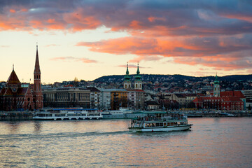 A beautiful and colorful sunset in Budapest, you can see a ferryboat crossing the Danube river
