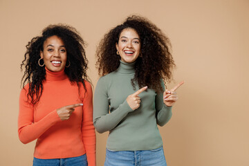Two swanky trendy cute young curly black women friends 20s wearing casual shirts clothes pointing...