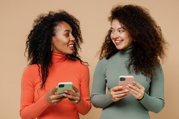 Two cheerful smiling young curly black women friends 20s wearing casual shirts clothes hold in hand...