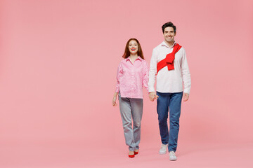 Full body smiling happy young couple two friends woman man 20s in shirt look camera hold hands isolated on plain pastel pink background studio portrait. Valentine's Day birthday holiday party concept.