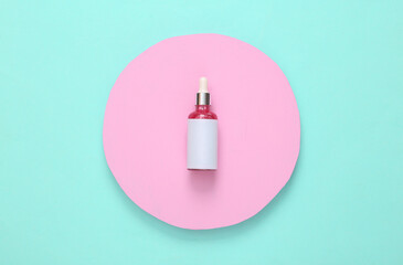 Bottle of face serum on pink circle. Turquoise background