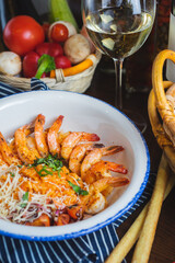 Traditional bright shrimp risotto in a bowl on a table in a restaurant with a beautiful decor in a dark key close-up.