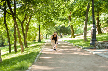 Fototapeta na wymiar Young fit woman tying the laces of sneakers in the park
