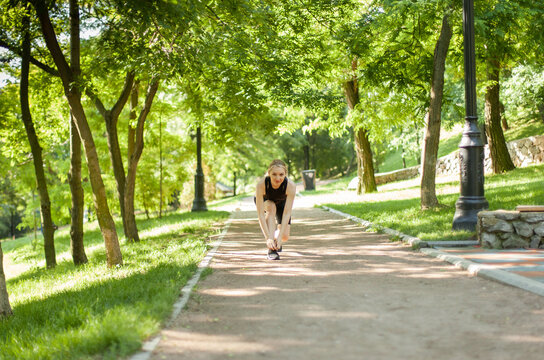Young fit woman tying the laces of sneakers in the park