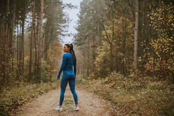 Obraz premium Young woman take a break during outdoor exercise on the forest trail at autumn