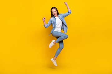 Full body photo of young optimistic lady yell jump wear jeans shirt shoes isolated on yellow color...